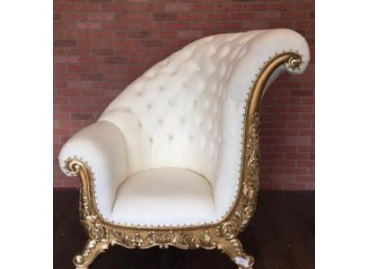 Белое кресло со спинкой напоминающей форму крыла птицы и в качестве дополнительных украшений присутствуют декоративные элементы золотого оттенка 